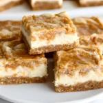 A stack of moist carrot cake bars with a rich cheesecake swirl